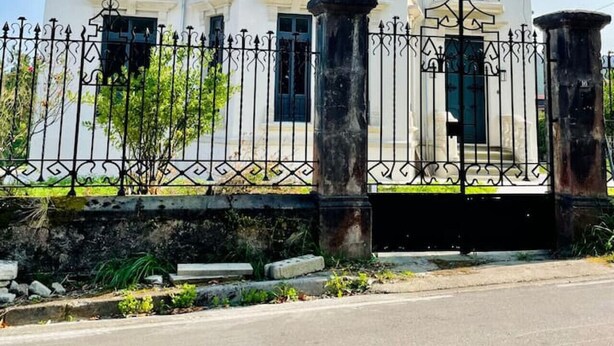 Un bâtiment à deux étages, doté d’une façade blanche, de nombreuses fenêtres et d’une clôture en métal noir.