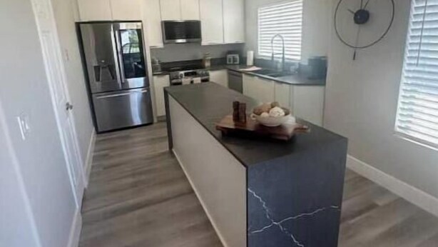 A modern kitchen with white cabinets, stainless steel appliances, and a marble island.