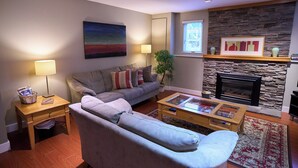 Un salon comprenant un canapé, une table basse, une lampe, une cheminée et des œuvres d’art.