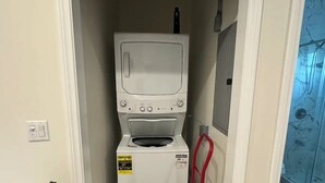 Ein Waschraum mit einer Waschmaschine und einem Trockner mit Frontlader, einem roten Sackkarren und einer weißen Tür.