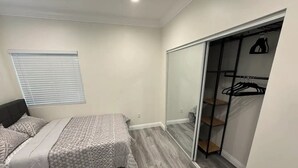 Ein Schlafzimmer mit einem Bett, einem Kleiderschrank und einem Fenster mit Jalousien.