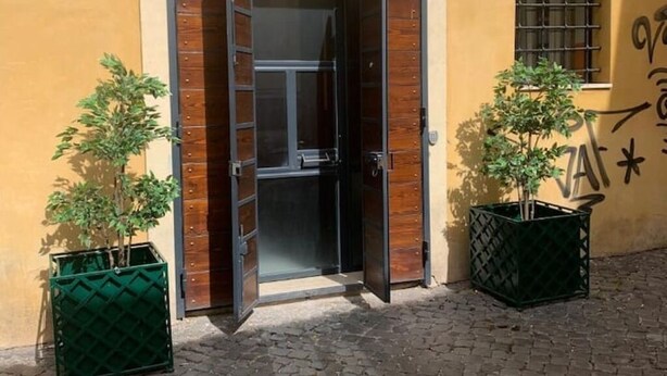 A building entrance with a wooden door and two potted plants on either side. - A.R.T. Loft Trastevere (Roma)