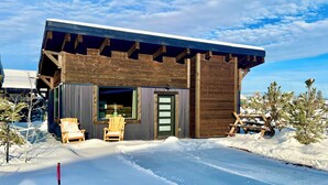 A wooden cabin with a covered patio area, a door, and a window.