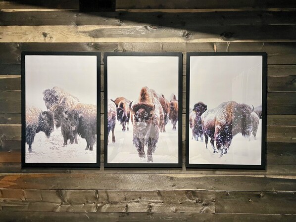 Three framed pictures of bison in a snowy landscape on a wooden wall.