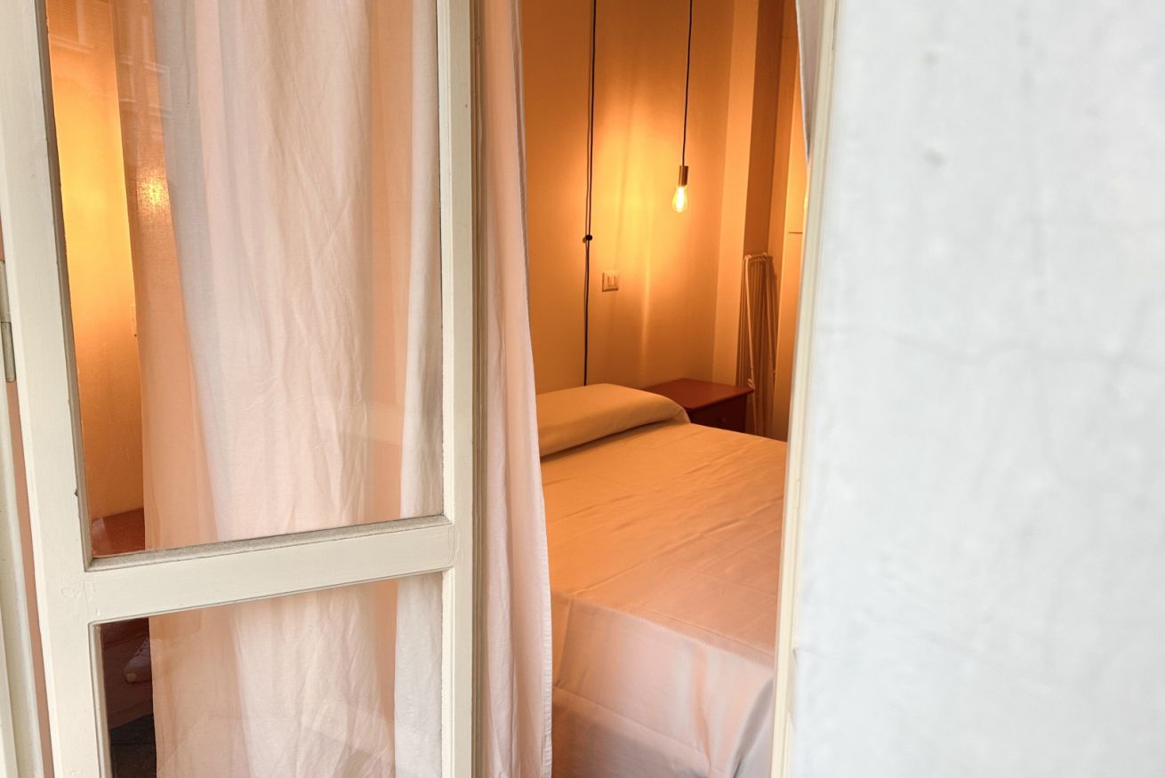 A bedroom with a bed, a nightstand, and a hanging light fixture.