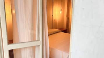 A bedroom with a bed, a nightstand, and a hanging light fixture.