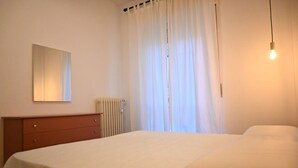 Une chambre à coucher comprenant un lit, une commode, un radiateur et un luminaire.