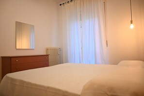 Une chambre à coucher comprenant un lit, une commode, un radiateur et un luminaire.