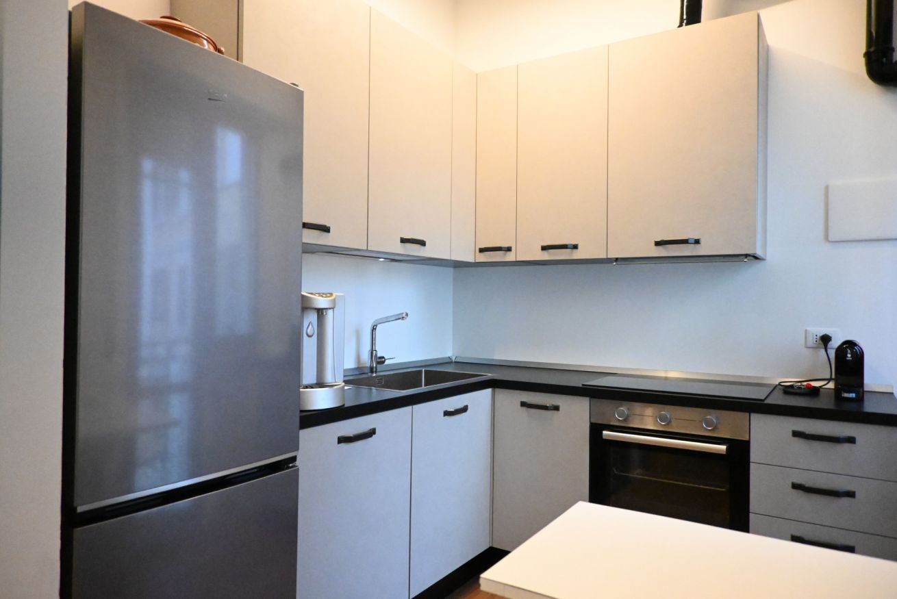 A modern kitchen with a refrigerator, stove, sink, and cabinets.