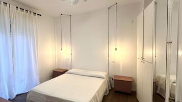 Een slaapkamer met een bed, nachtkastjes, een kledingkast en een plafondventilator.