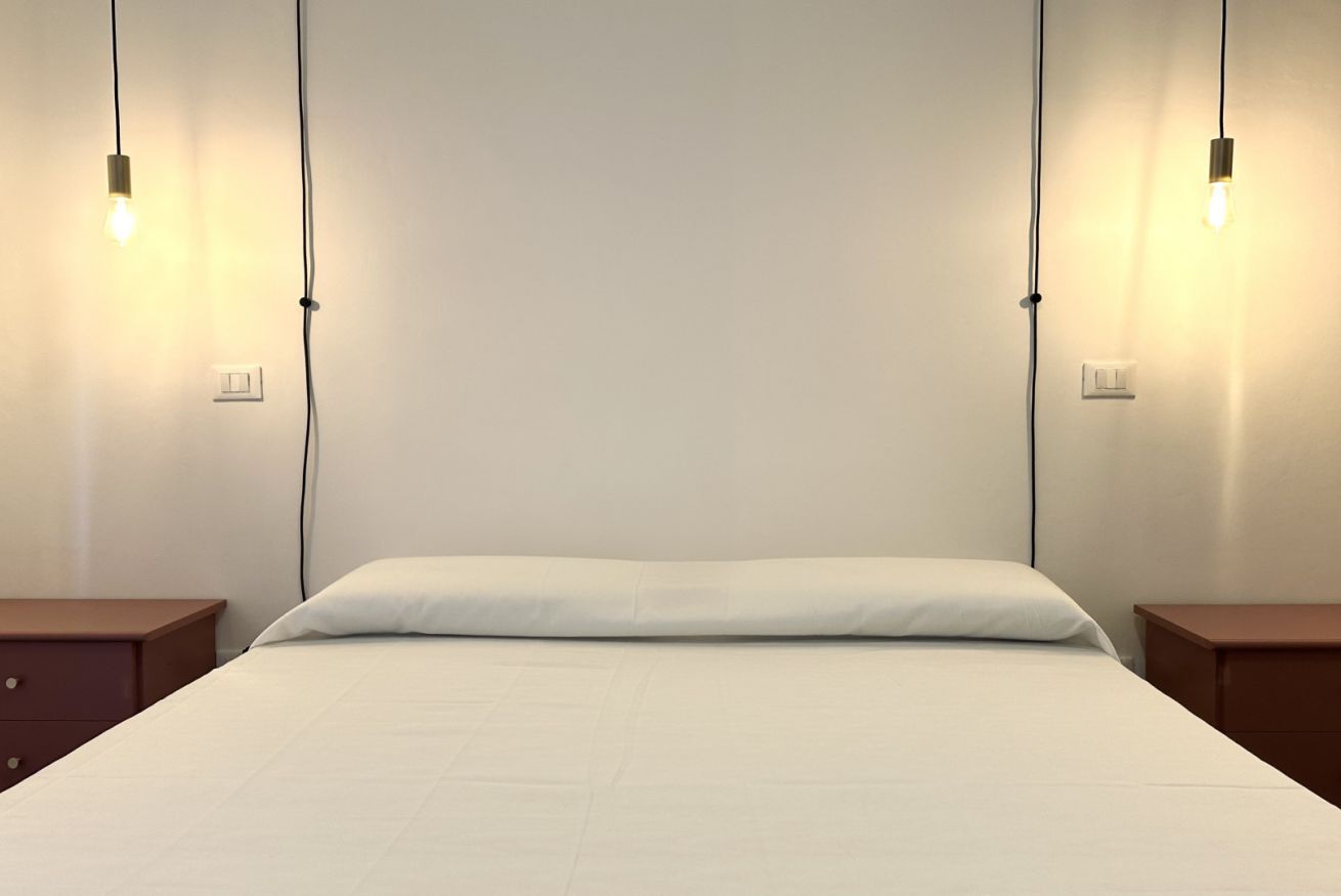 Ein Bett mit weißer Bettdecke, zwei Nachttische und zwei Wandleuchten.
