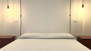 Ein Bett mit weißer Bettdecke, zwei Nachttische und zwei Wandleuchten.