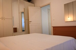 Un dormitorio con cama, armario, espejo y cómoda.
