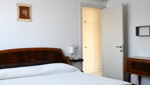 Una camera d'albergo con un letto in legno, un comodino con una lampada, un armadio e un quadro appeso al muro.