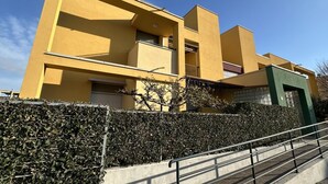 Un edificio moderno con facciata gialla, diversi balconi e una sezione verde sulla destra.