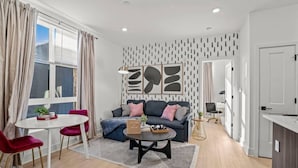 A modern living room with a sofa, a coffee table, and a dining area with a table and chairs.