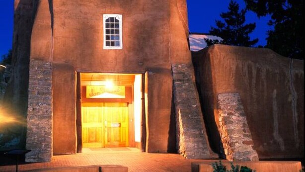 Una iglesia con cruz en la parte superior, una ventana pequeña y una entrada acogedora.