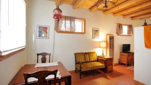 Una habitación con una mesa de comedor de madera, un sofá, un televisor y una lámpara.