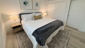 A bedroom with a bed, two bedside tables, a nightstand, a rug, and a wardrobe.