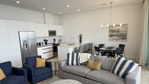 A modern living room with a grey sofa, blue armchairs, and a marble coffee table.