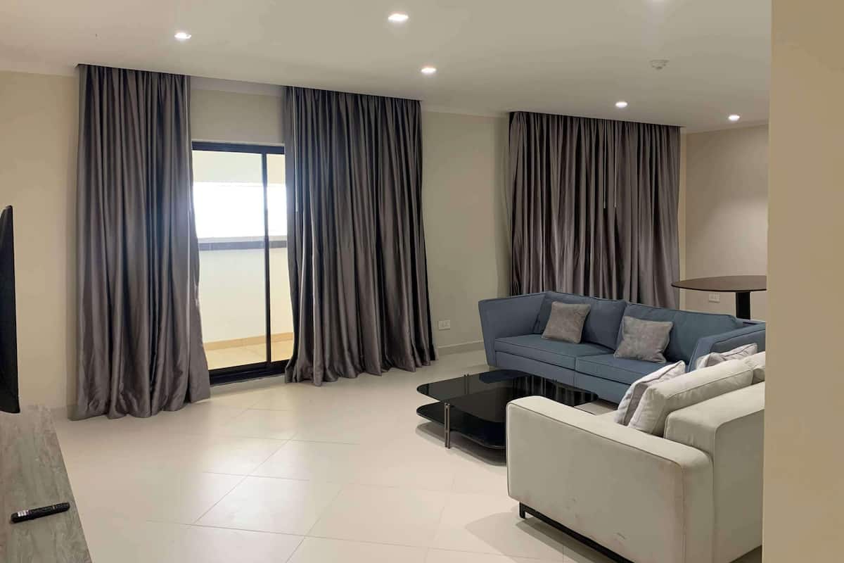 A modern living room with a blue sofa, a white sofa, and a glass coffee table.