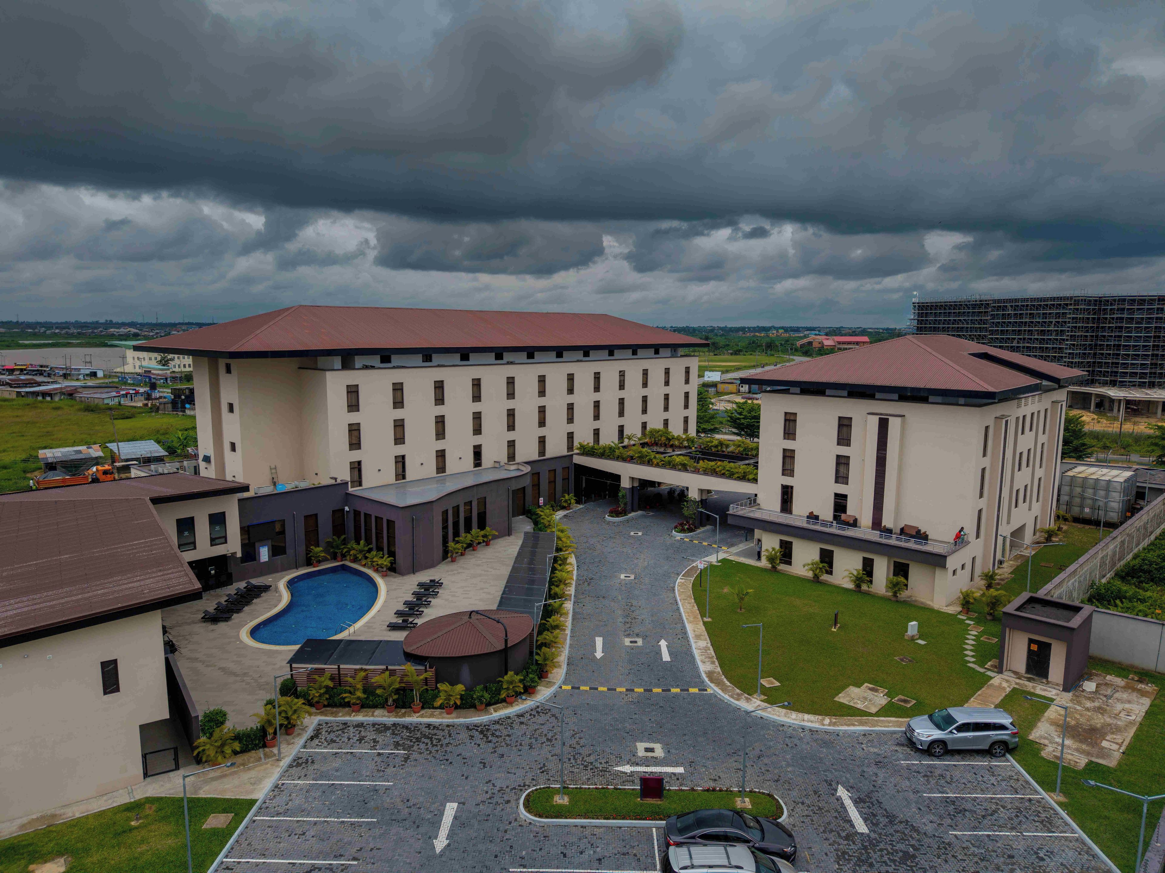 A hotel with a swimming pool, a covered outdoor area, and a parking lot.