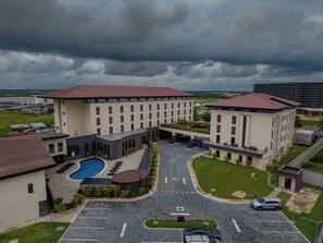 A hotel with a swimming pool, a covered outdoor area, and a parking lot. - Best Western Plus At The Oxbow Lake (Yenagoa)