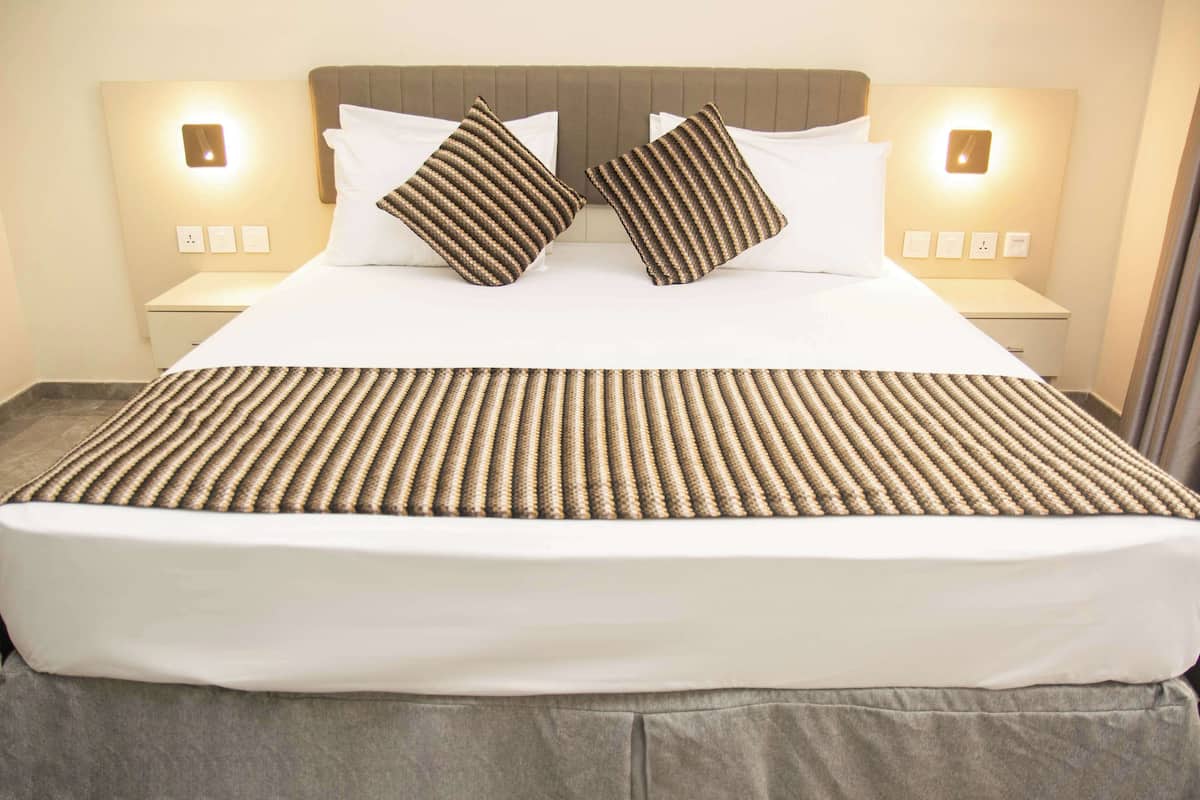 A neatly made bed with a striped bedspread and two pillows, flanked by bedside tables with wall-mounted lamps.