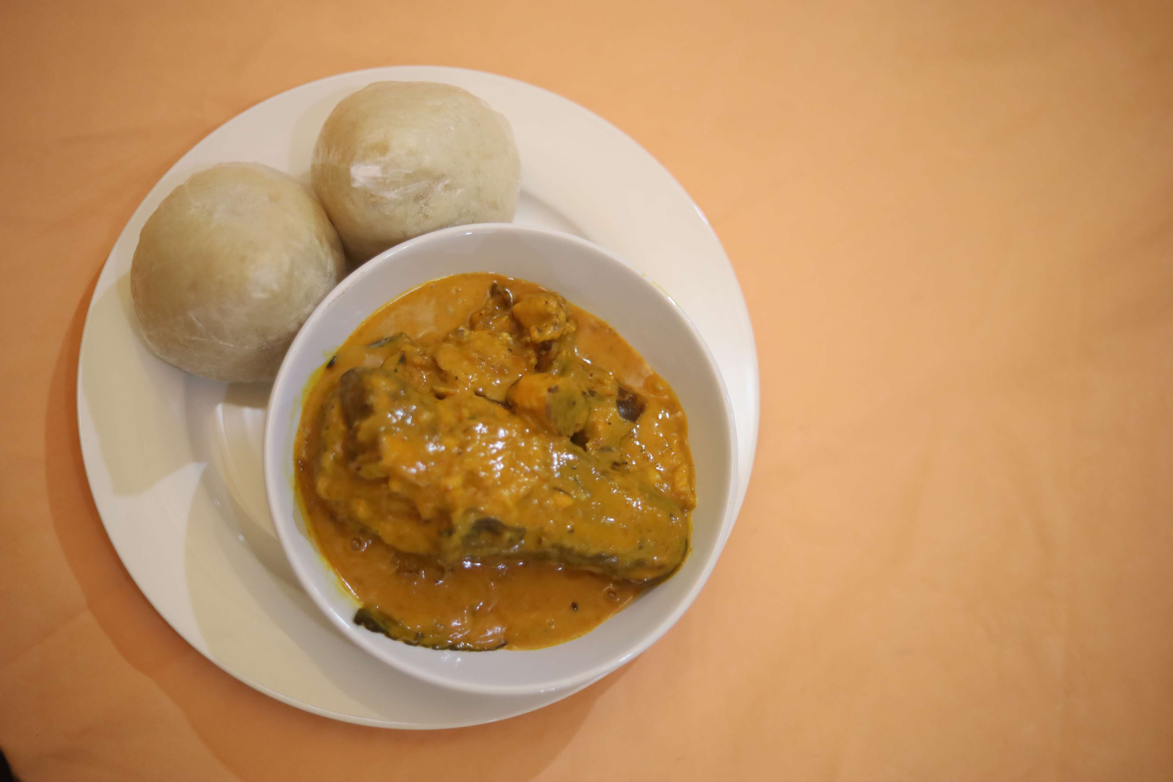 A plate with two dumplings and a bowl of curry.