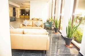 A spacious lobby with a beige sofa and armchairs, a reception desk, and potted plants. - Best Western Plus At The Oxbow Lake (Yenagoa)
