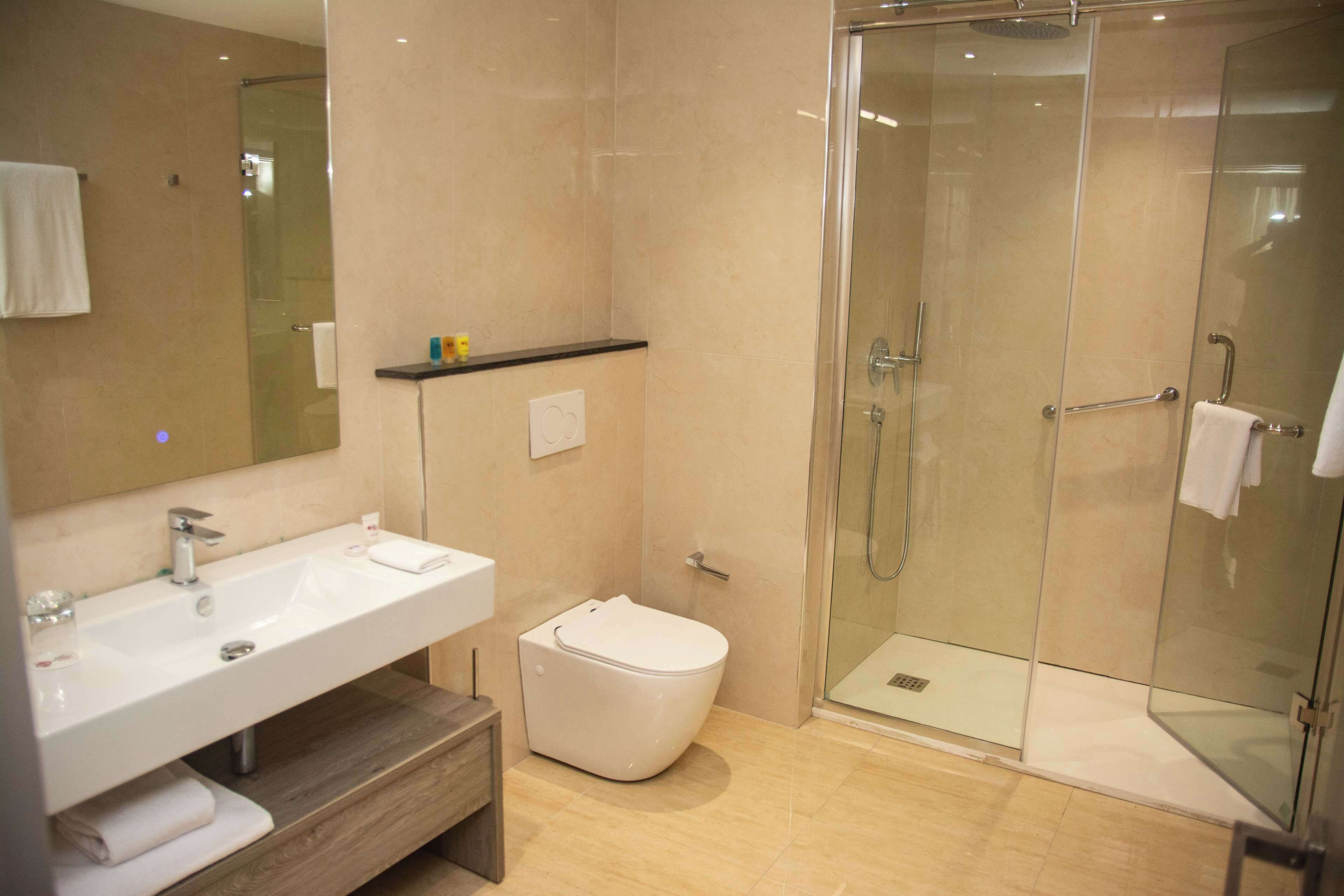 A modern bathroom with a glass-enclosed shower, a white sink, and a toilet.