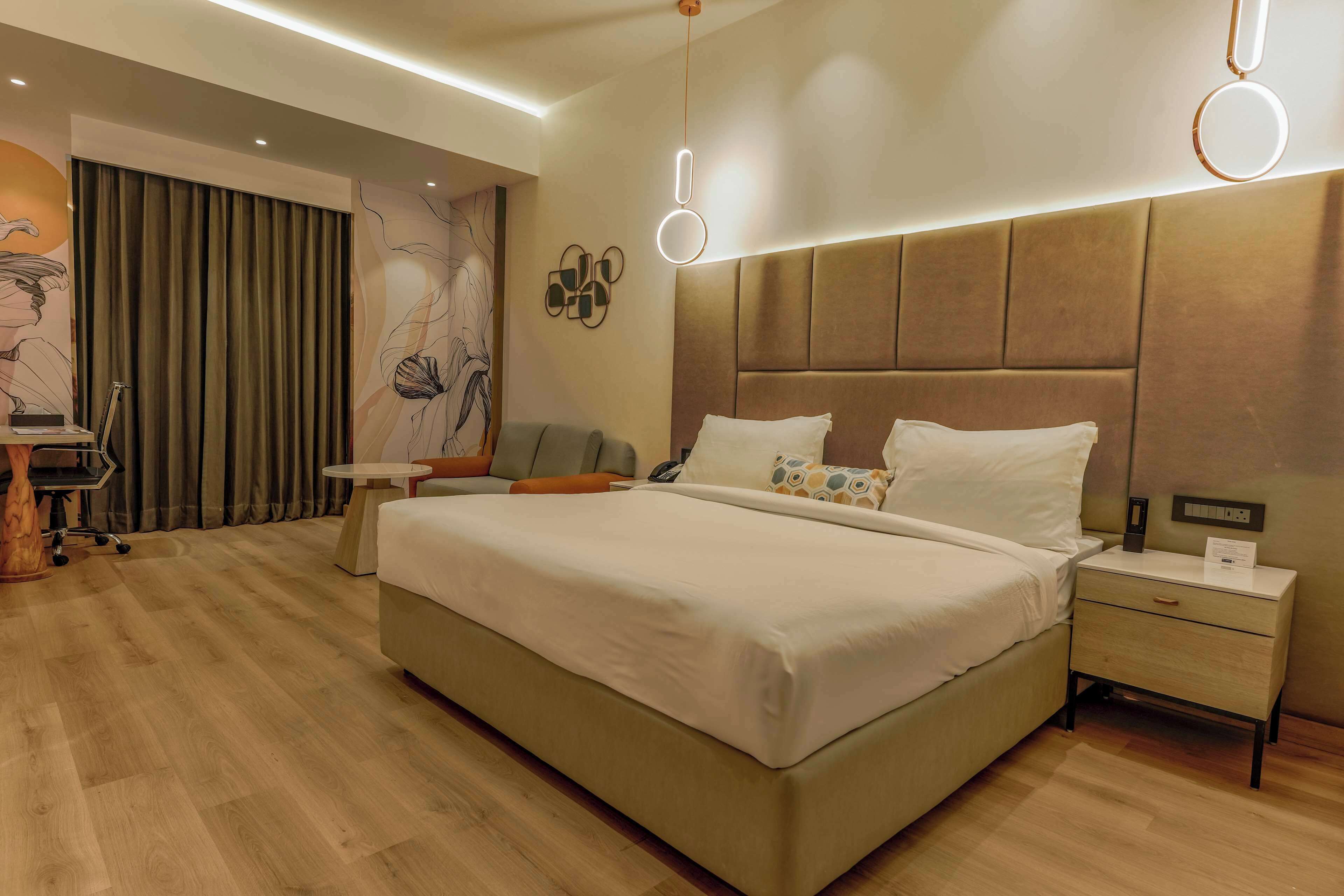 A modern hotel room with a large bed, bedside tables, a desk, and a chair.