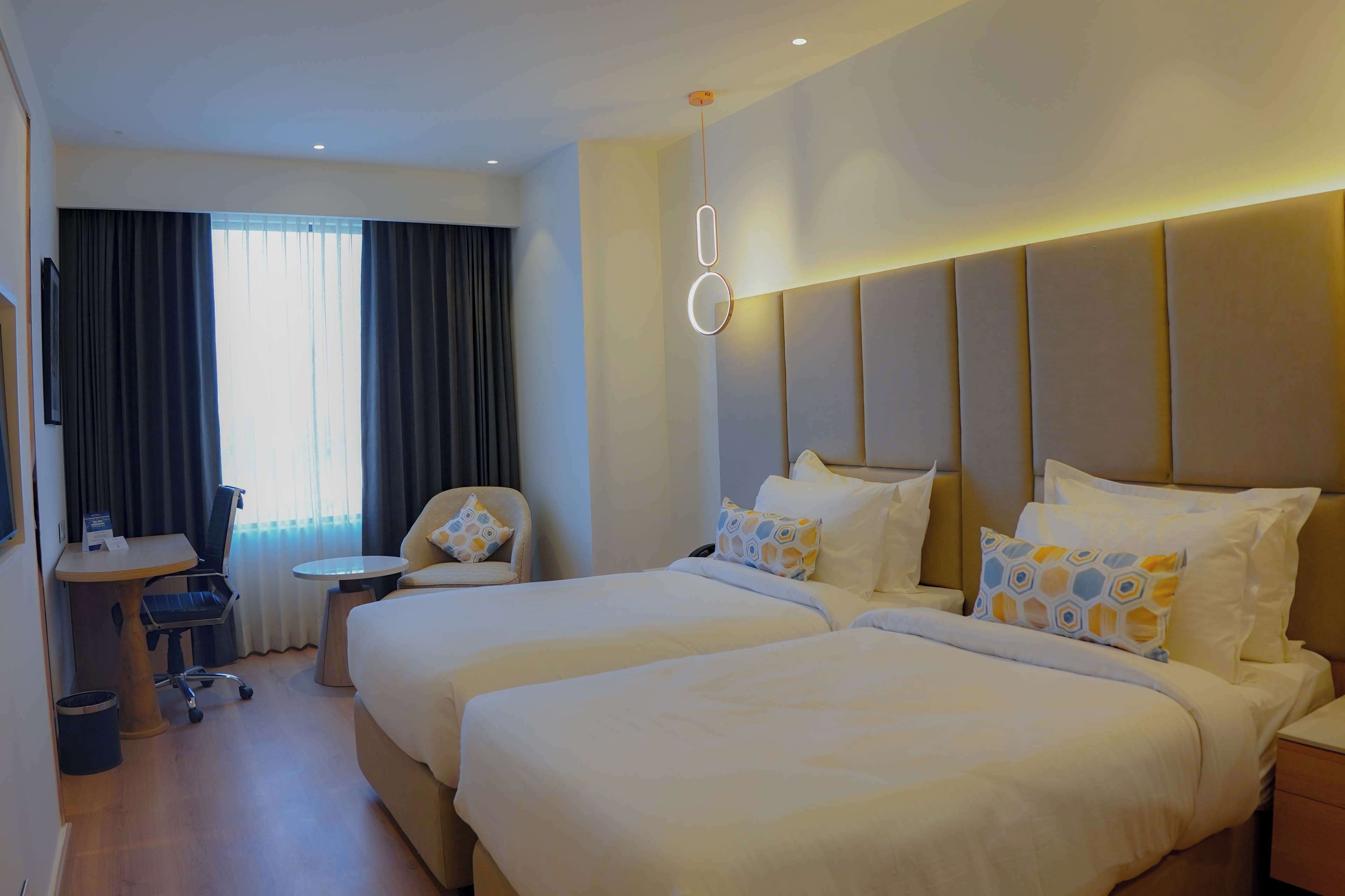 Une chambre d’hôtel avec deux lits, un bureau, une chaise et une petite table.