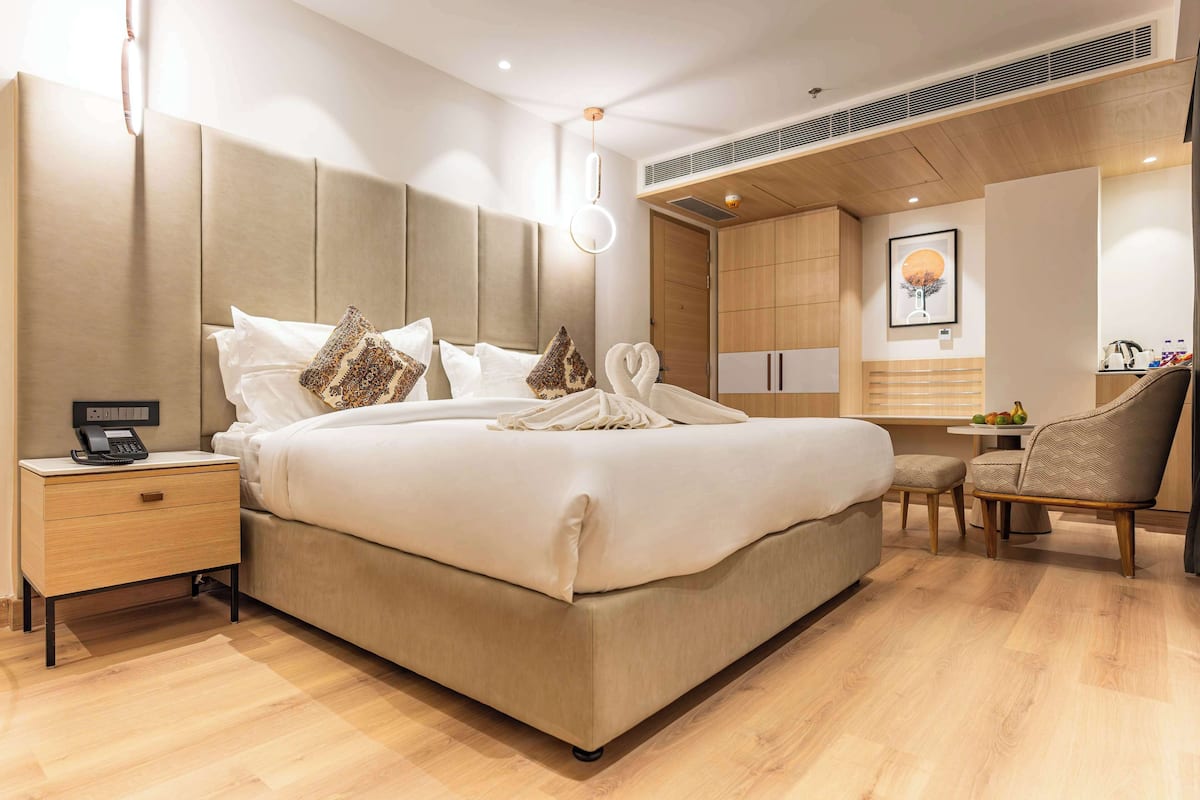 Quarto de hotel moderno com uma cama grande, mesa de cabeceira e uma pequena área de trabalho.