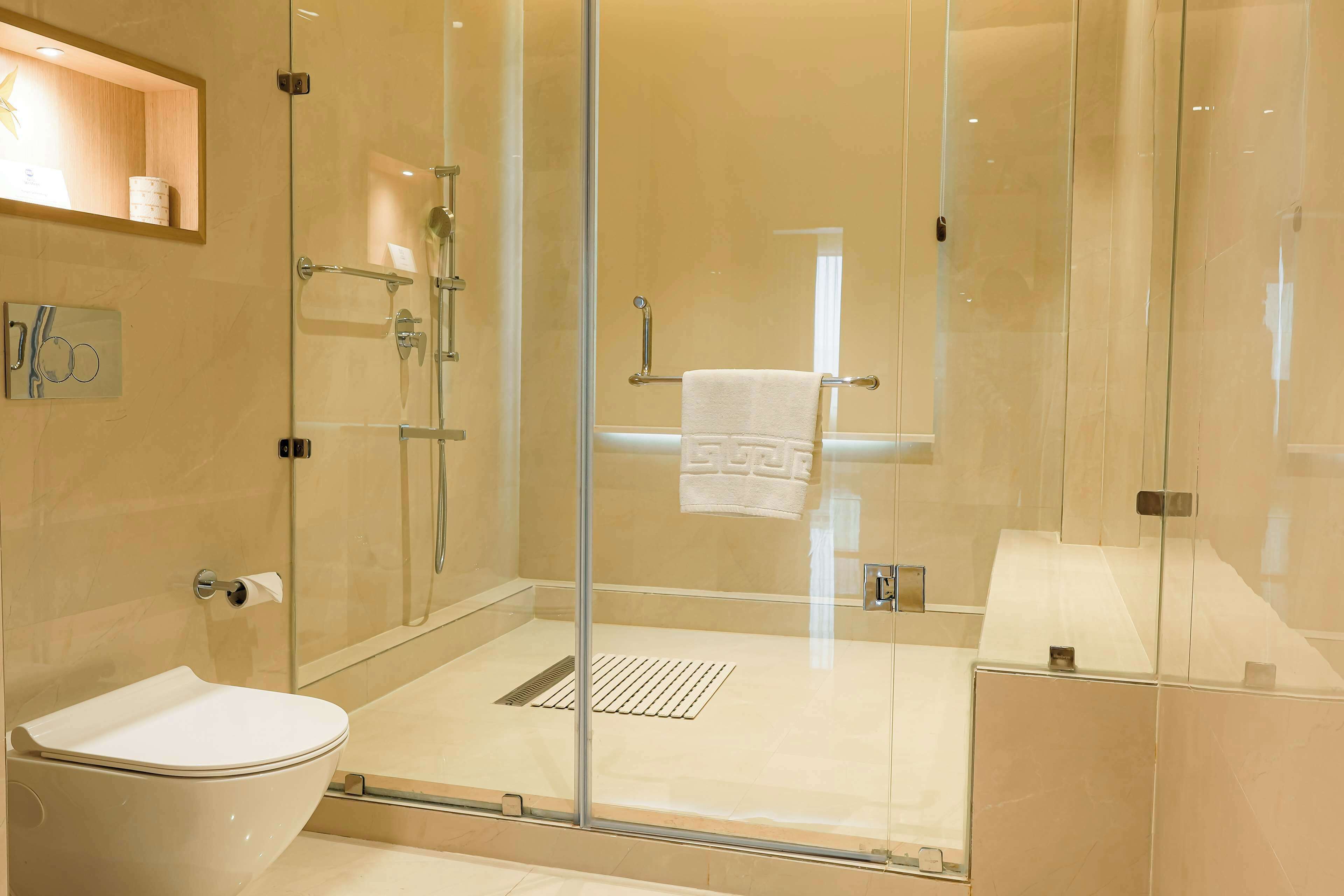 A modern bathroom with a glass-enclosed shower, a toilet, and a sink.