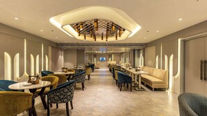 A modern hotel lobby with a central seating area, a long table, and a television screen. - Best Western Ah1 Amritsar (Amritsar)