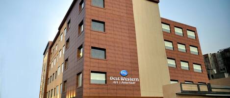 Un hotel de varios pisos con un llamativo letrero de 'Best Western', un diseño arquitectónico moderno y una entrada visible.