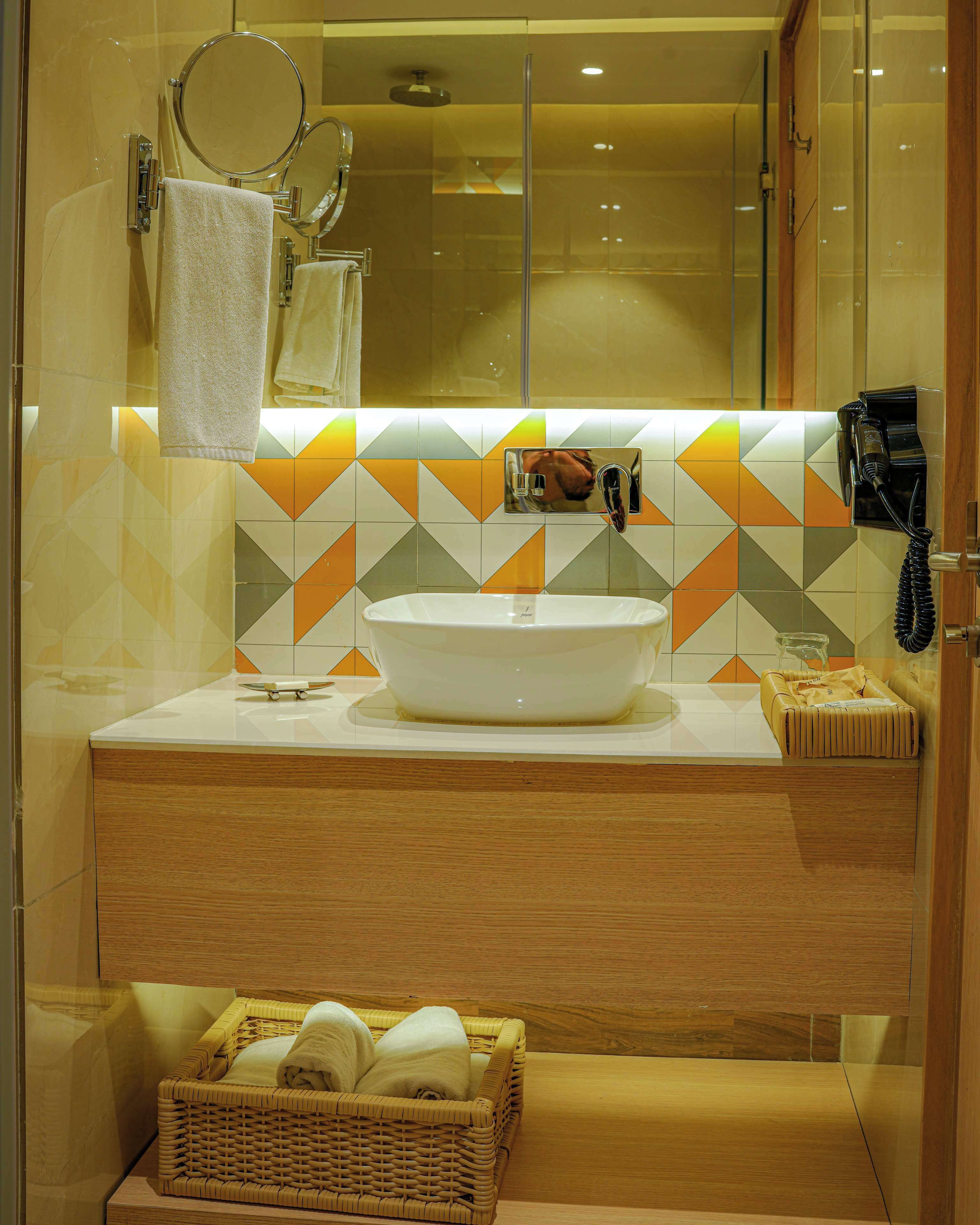 A bathroom with a large mirror, a sink, and a towel rack.