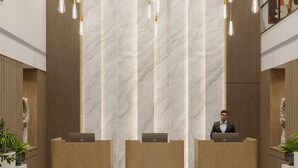 A modern reception area with three wooden reception desks, marble walls, and hanging pendant lights. - Best Western Ah1 Amritsar (Amritsar)