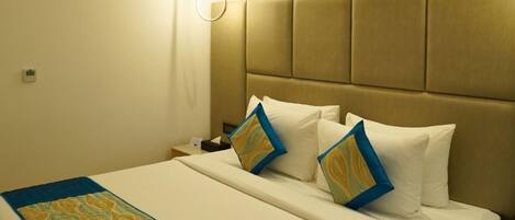 Una habitación de hotel con una cama grande, un cabecero y una mesita de noche.