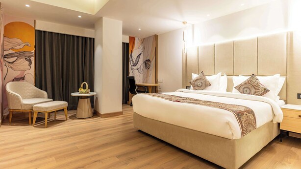 A modern hotel room with a large bed, a chair, a small round table, and a wall art piece. - Best Western Ah1 Amritsar (Amritsar)