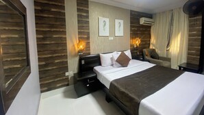 Ein Hotelzimmer mit einem großen Bett, einem Schreibtisch, einem Stuhl und zwei Wandleuchten.