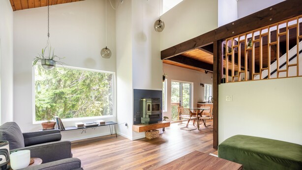 Ein geräumiges Wohnzimmer mit großem Fenster, Kamin und Treppe.