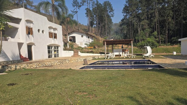 Una casa moderna con piscina, area salotto esterna e un pergolato.