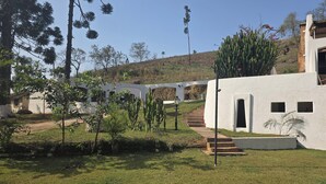 Un edificio bianco con una scala che conduce a una porta, immerso nel verde e circondato da cactus.