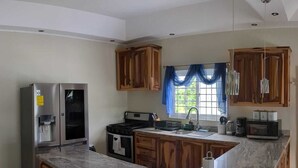 Une cuisine avec des meubles en bois, un réfrigérateur en acier inoxydable, une cuisinière et un plan de travail en marbre.