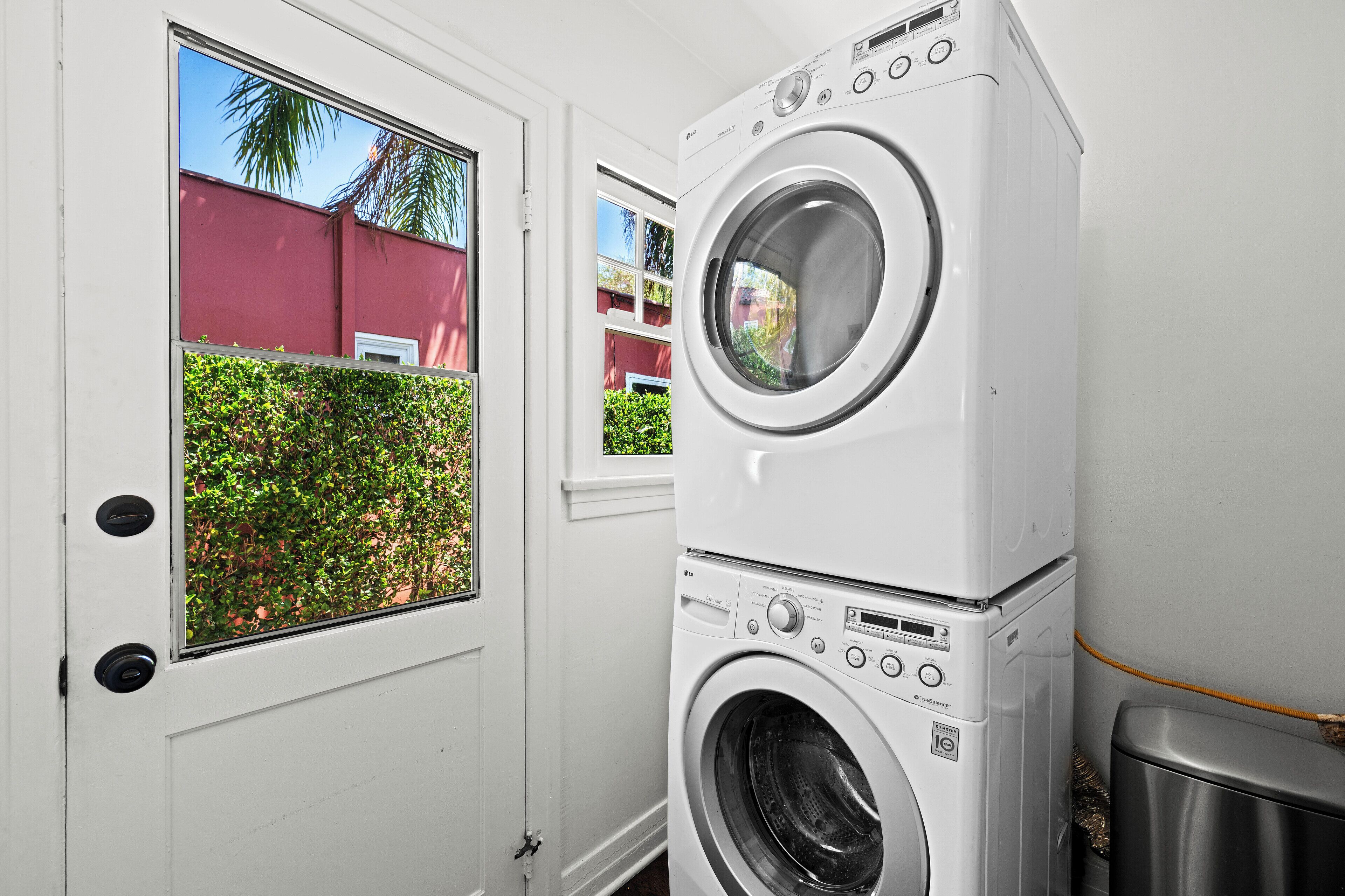 A stacked washer and dryer unit in a room with a white door and windows.