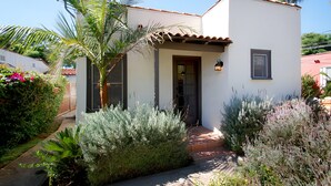 Una casa moderna de dos pisos con fachada blanca, techo de tejas y un pequeño porche frontal con escalones.