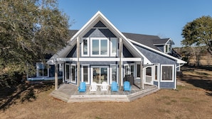 A two-story house with a covered porch, multiple windows, and a deck area with chairs. - Whitehurst Lookout on the Sound (Beaufort)