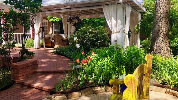 A covered patio area with a brick pathway leading to a seating area under a pergola.